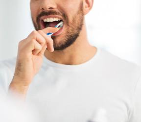 Man smiling while brushing his teeth