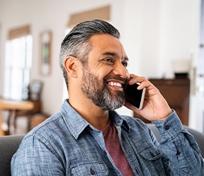 Man smiling while talking on phone at home