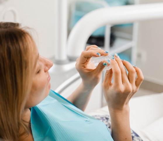 Patient holding clear aligner in treatment chair