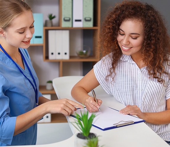 Team member and patient reviewing dental federal enrollment forms