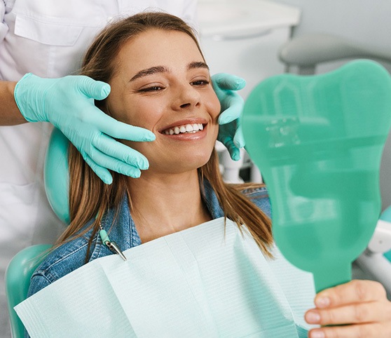 Woman smiling at reflection in handheld mirror