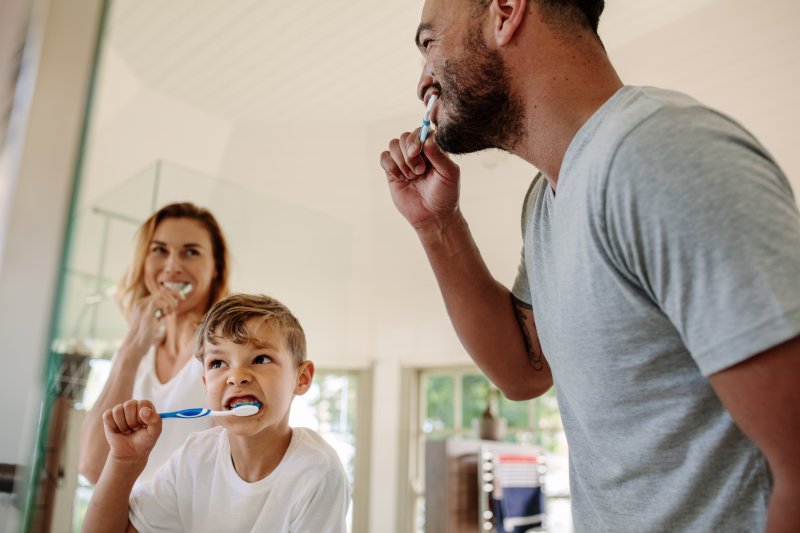 Family smiling while brushing their teeth together